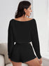 Back view of woman in black textured loungewear set showing off-shoulder design and shorts