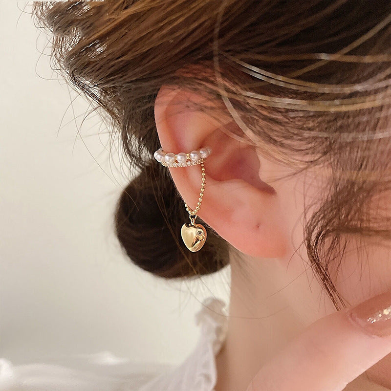 Pearl and rhinestone ear cuff with gold heart charm on chain, worn on ear with brown hair