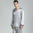 Model wearing silver silk pajamas with diamond pattern, button-up top, standing against gray background