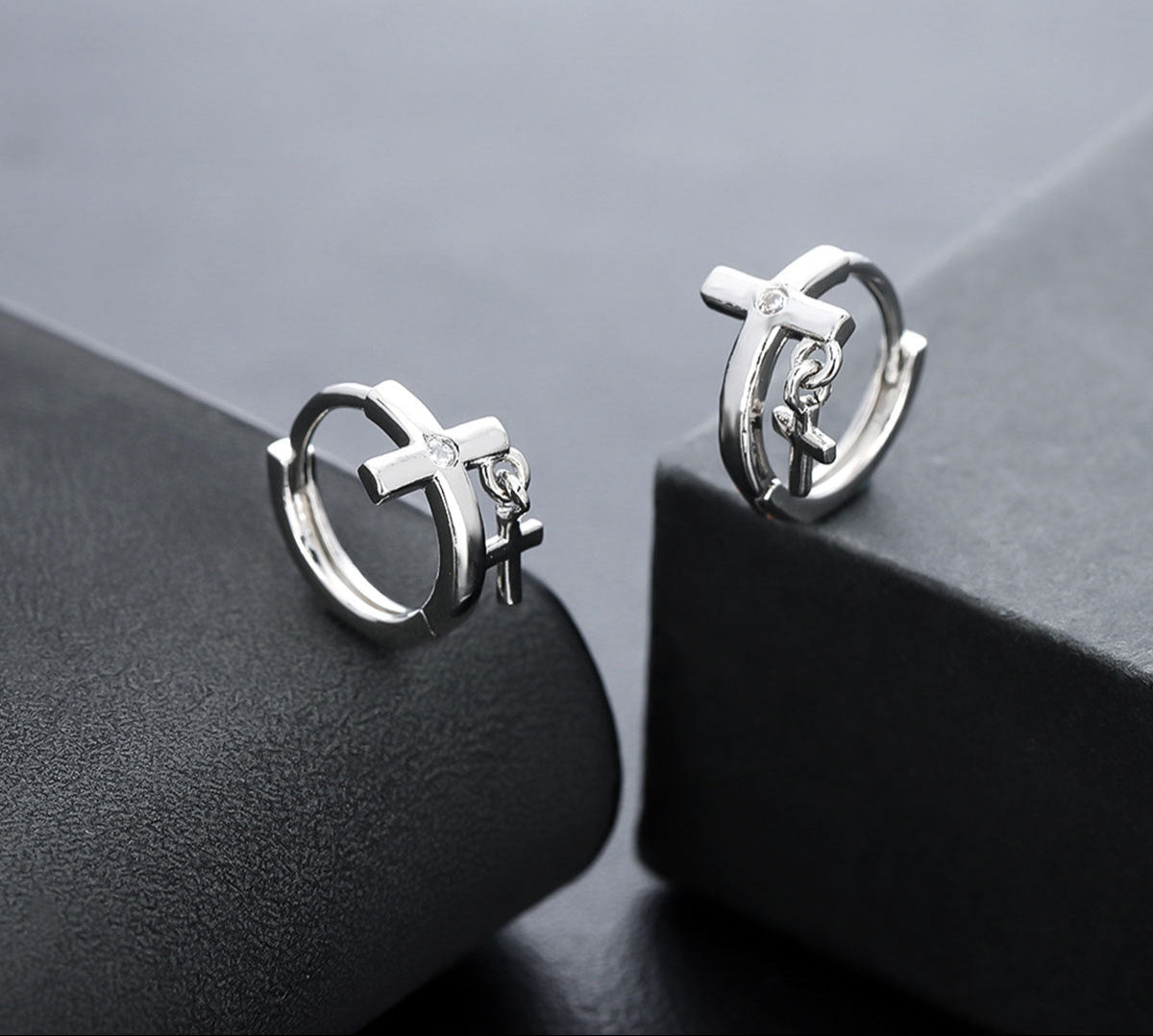 Silver cross hoop earrings with zircon accents on gray backdrop