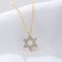 A gold Star of David pendant necklace with crystal embellishments displayed on white fabric. The six-pointed star features pave diamonds on a delicate chain