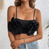 Woman wearing a black crop top with oversized 3D floral appliqués and thin straps, paired with light-wash denim jeans.
