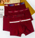 Four burgundy men's underwear styles with different waistbands arranged on decorative surface against light background
