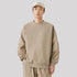 Male model wearing a beige oversized sweatshirt with "NoProblem" embossed on the chest, paired with matching sweatpants and a baseball cap