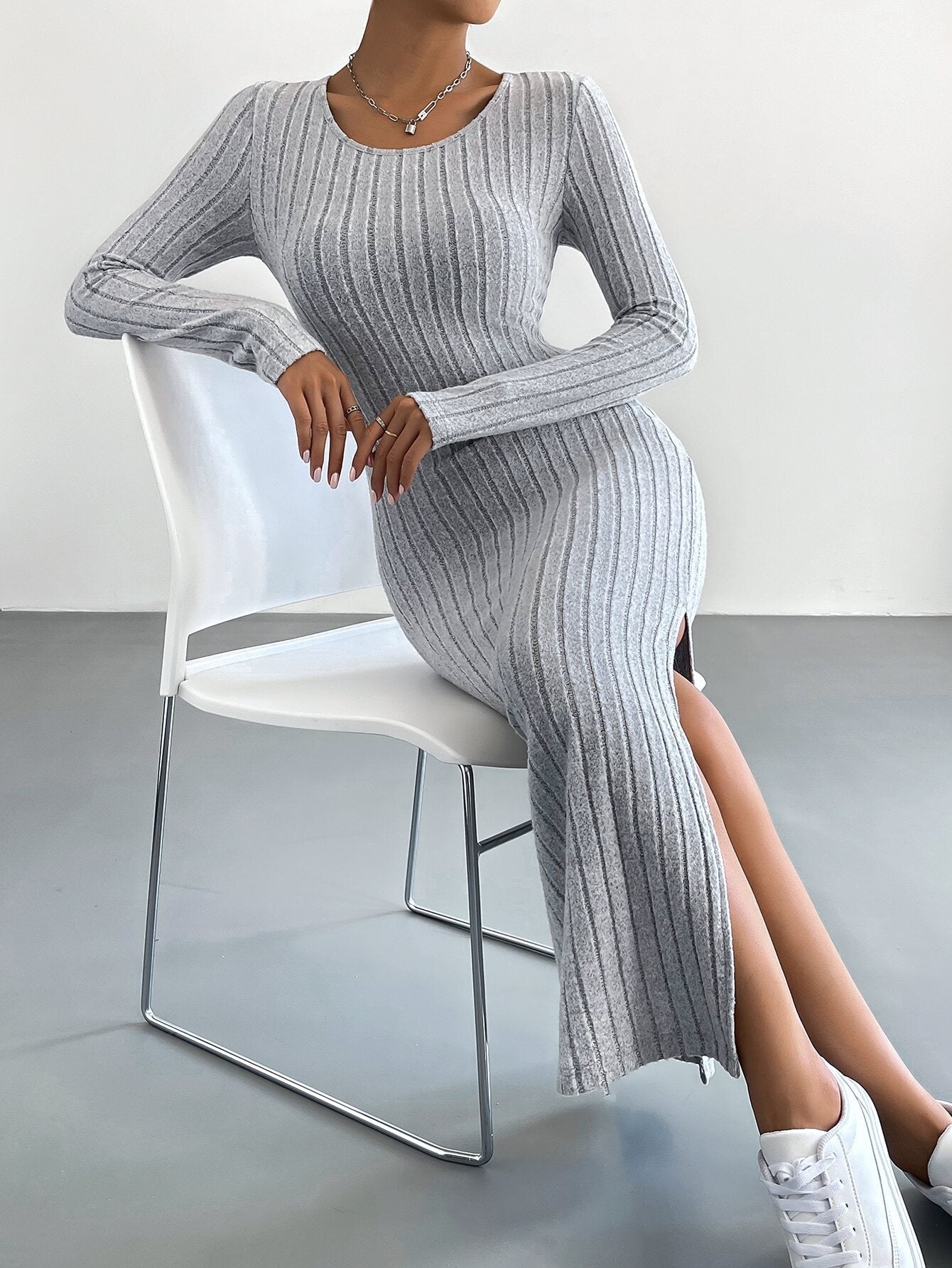 Gray ribbed bodycon dress with side slit, seated on white chair with white sneakers