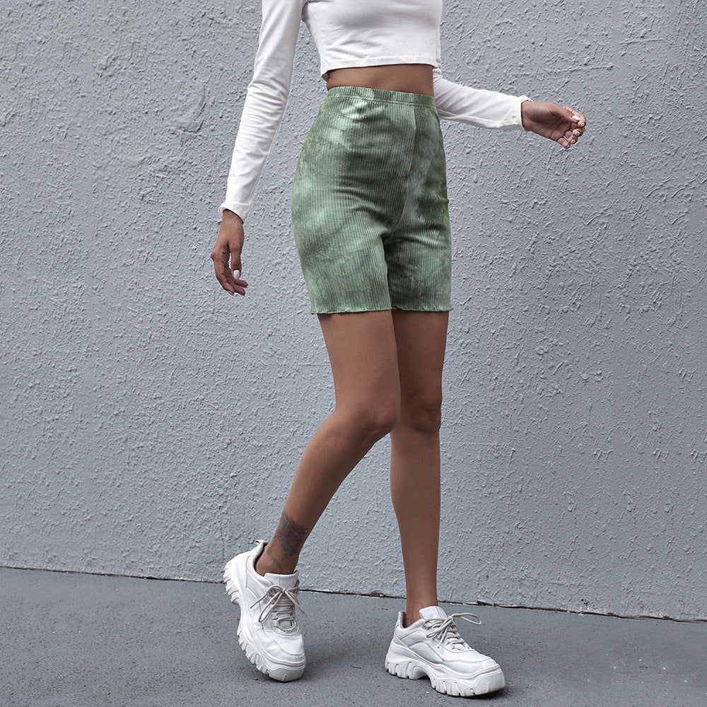 Model walks in green tie-dye ribbed biker shorts and a white cropped top, styled with platform sneakers