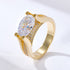 A gold engagement ring with large oval diamond centerpiece and pave diamond accents on band against white background