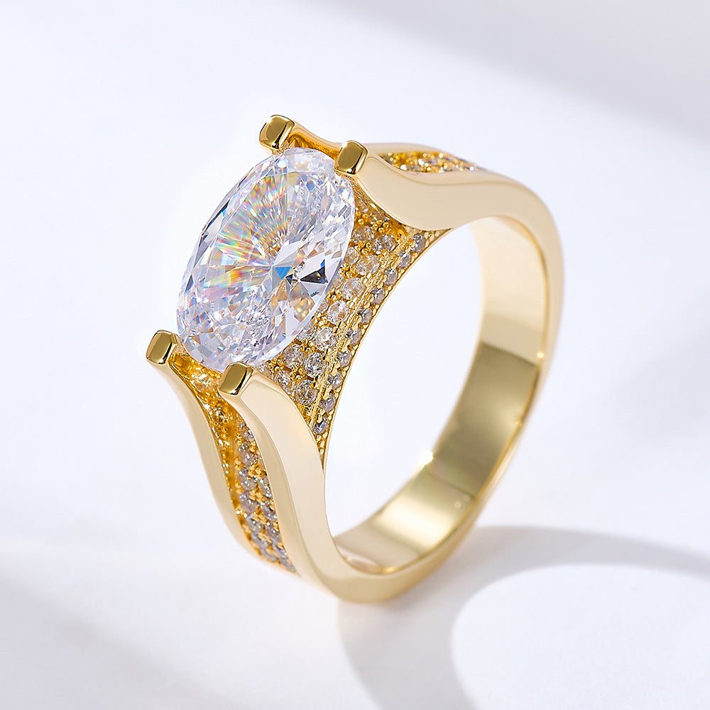 A gold engagement ring with large oval diamond centerpiece and pave diamond accents on band against white background