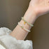 Pearl and jade beaded bracelet with a gold-toned charm, showcasing alternating white pearl and light green jade stones, worn with a white textured fabric