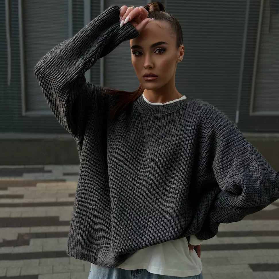 Woman in black oversized sweater with long sleeves and hair pulled back, industrial background with venetian blinds