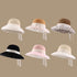 A collection of six woven sun hats in beige, brown, pink, black, and vanilla each featuring a lace-trimmed brim and tied ribbons, displayed against a neutral background.