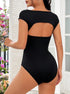 Back view: Open-back black bodysuit with a curved cutout and cap sleeves, paired with floral background decor.