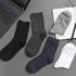 Stack of folded socks in various neutral colors placed on a laptop