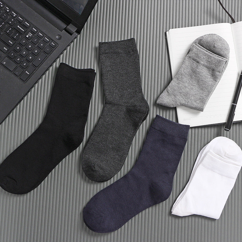 Stack of folded socks in various neutral colors placed on a laptop