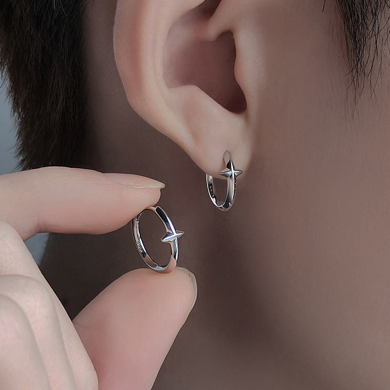 Silver star hoop earring worn on ear, with fingers holding another earring