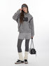 Winter layered look featuring grey textured hoodie with '08' graphic, cable knit shorts over leggings, cream leg warmers, and black sneakers. Styled with black shoulder bag