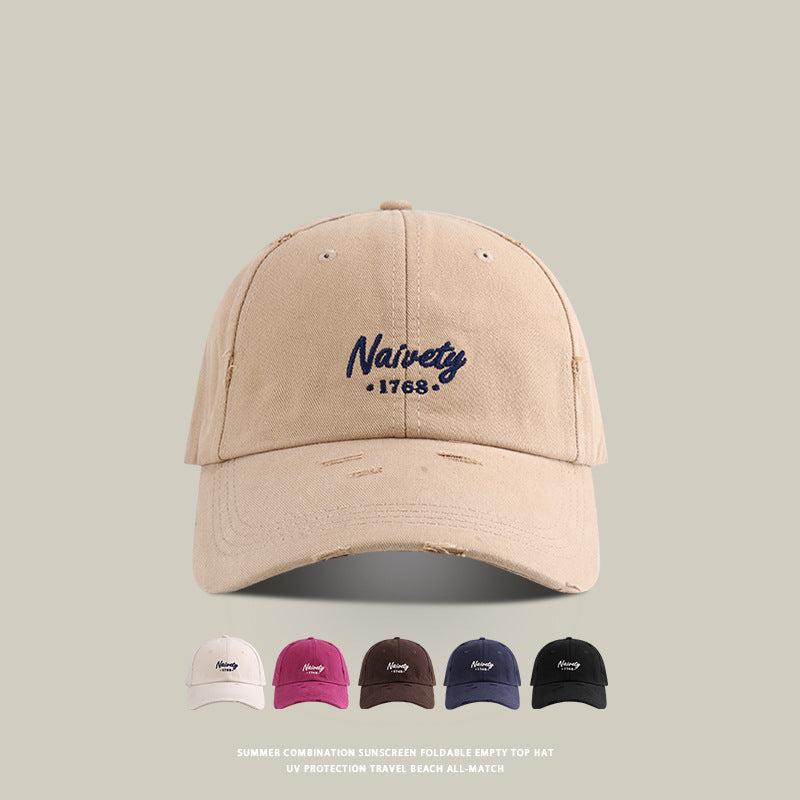 Beige baseball cap with 'Naivety 1768' embroidered logo and color variants shown below