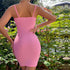 A woman in a pink ribbed bodycon mini dress stands with hand on hip, showing back view, surrounded by garden plants