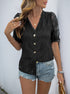 Woman wearing a black lace blouse with V-neckline, puff sleeves, and button-down front, paired with distressed denim shorts and gold jewelry.