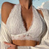 A woman wearing a white lace bralette with deep V-neck and intricate floral pattern, paired with a silk robe