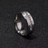 A silver stainless steel ring with embedded square-cut stones, placed on a dark, textured surface for a sleek and modern look.
