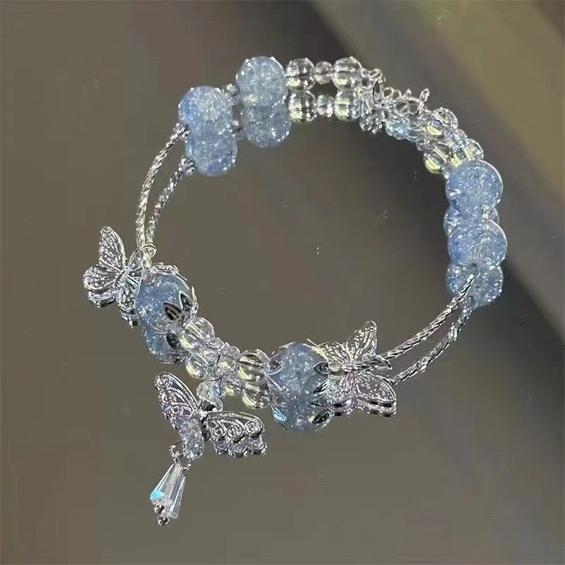 Crystal bracelet with silver butterfly charms and dangling teardrop pendant, made with light blue crackle beads