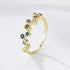 A woman wearing gold bubble rainbow ring with colorful gemstones in bezel settings on white background