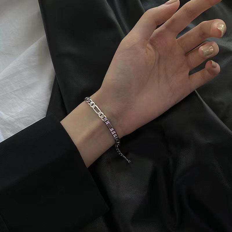 Silver Figaro chain bracelet on wrist, close-up view