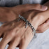 Silver chain bracelet with cross pendants worn on a wrist, adding a stylish and edgy touch to a casual outfit.