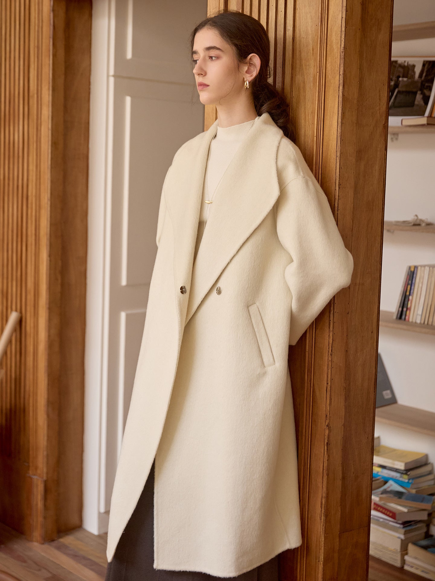 Side view of cream wool coat showing dropped shoulder seam and double-breasted button detail