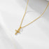 Gold cross pendant necklace with diamond pavé setting on delicate chain, displayed on white surface with subtle shadow casting
