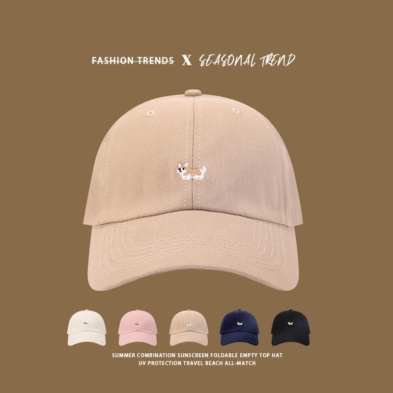 Beige baseball cap with small embroidered corgi dog logo, displayed with color variants in white, pink, navy, and black