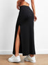 Black long skirt with side slit, showcasing a rear view with white platform sneakers