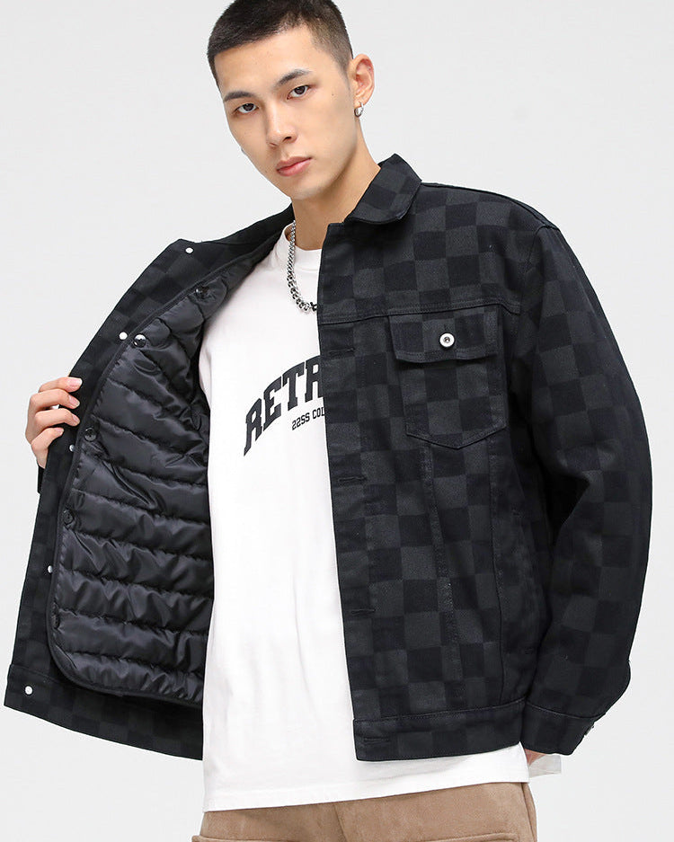 A model is showing the quilted lining of a black checkered jacket over white graphic tee and tan pants against white backdrop