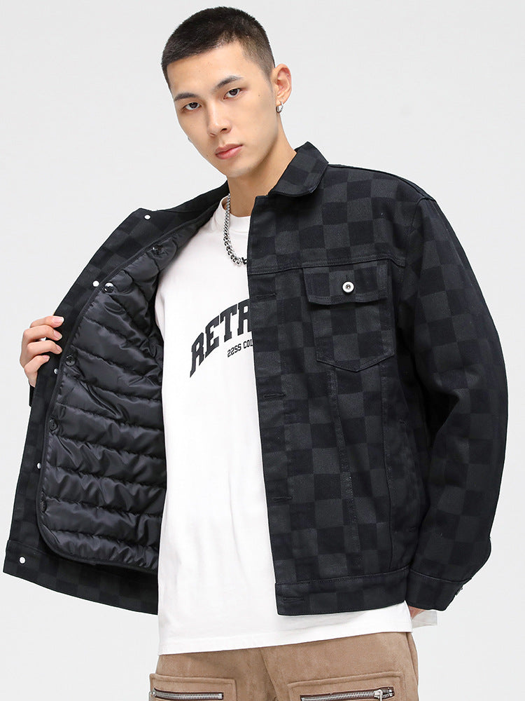 A model is showing the quilted lining of a black checkered jacket over white graphic tee and tan pants against white backdrop