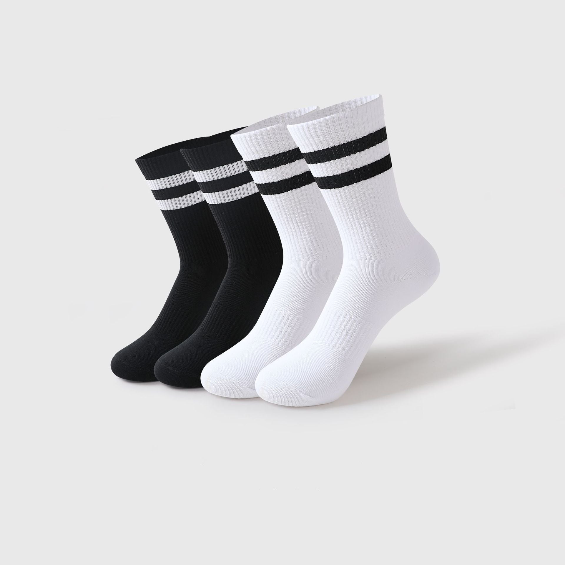 A set of four athletic crew socks in black and white, each featuring two bold black stripes near the top, displayed against a plain white background