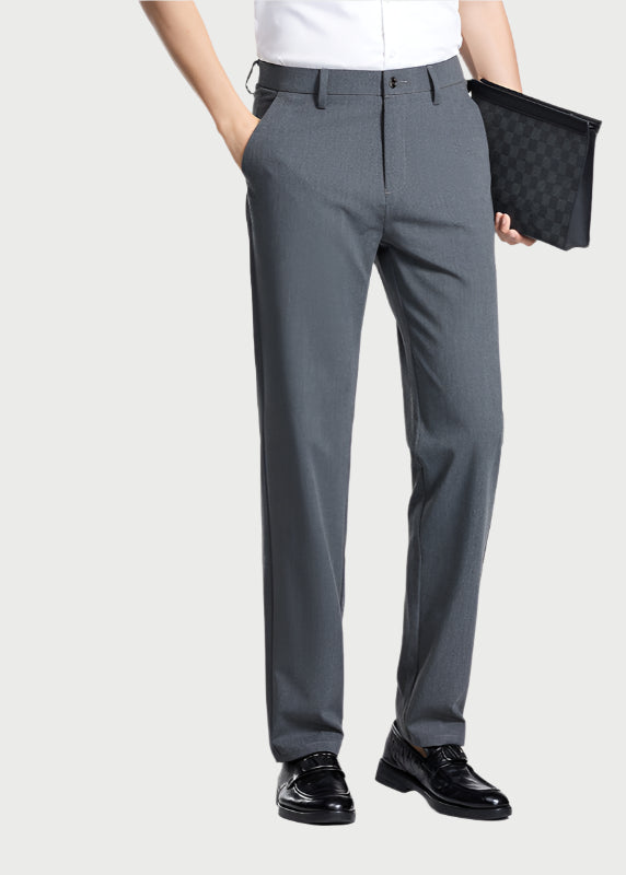 Model wearing gray dress pants with white shirt, holding black clutch, shown from waist down with polished shoes