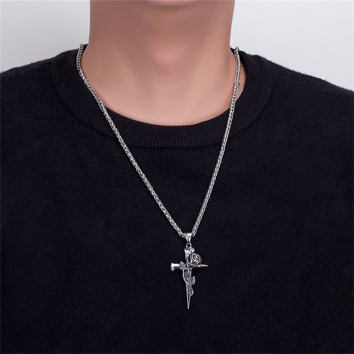 A model wearing a black sweater with silver rose cross pendant necklace on box chain against neutral background