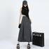 Front view of gray maxi skirt with clean pleats, paired with black asymmetric top and chunky black sandals