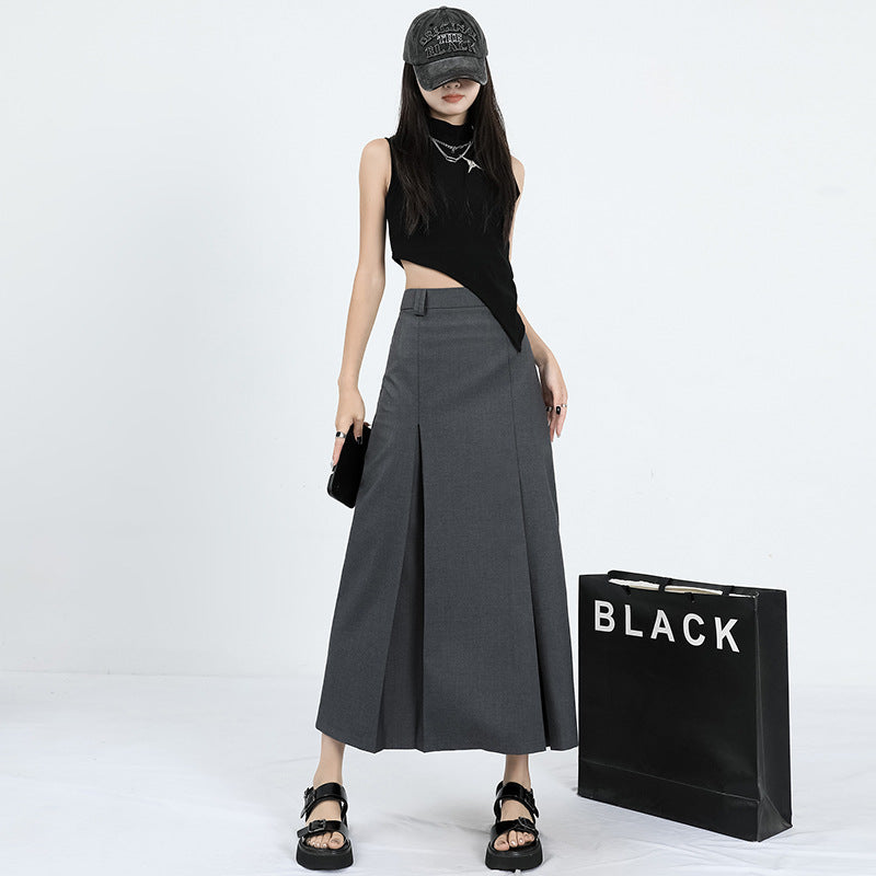 Front view of gray maxi skirt with clean pleats, paired with black asymmetric top and chunky black sandals