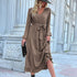 A model in taupe tiered maxi dress with v-neck and balloon sleeves is styled with black wide-brim hat, ankle boots and clutch for fall fashion