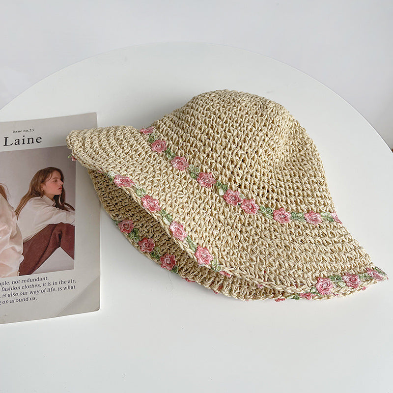 A soft beige straw hat decorated with delicate pink flowers, blending elegance and practicality for a chic summer accessory.