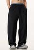Male model in black wide-leg sweatpants with a contrast waistband, styled with grey sneakers for a casual streetwear look.