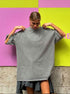 Person wearing a gray oversized t-shirt against a colorful background