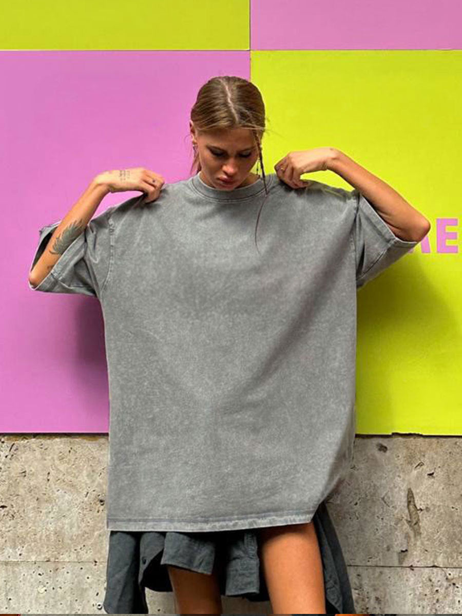Person wearing a gray oversized t-shirt against a colorful background