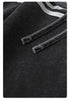 Close-up of gray drawstring detail on black track pants showing contrast stitching and textile texture