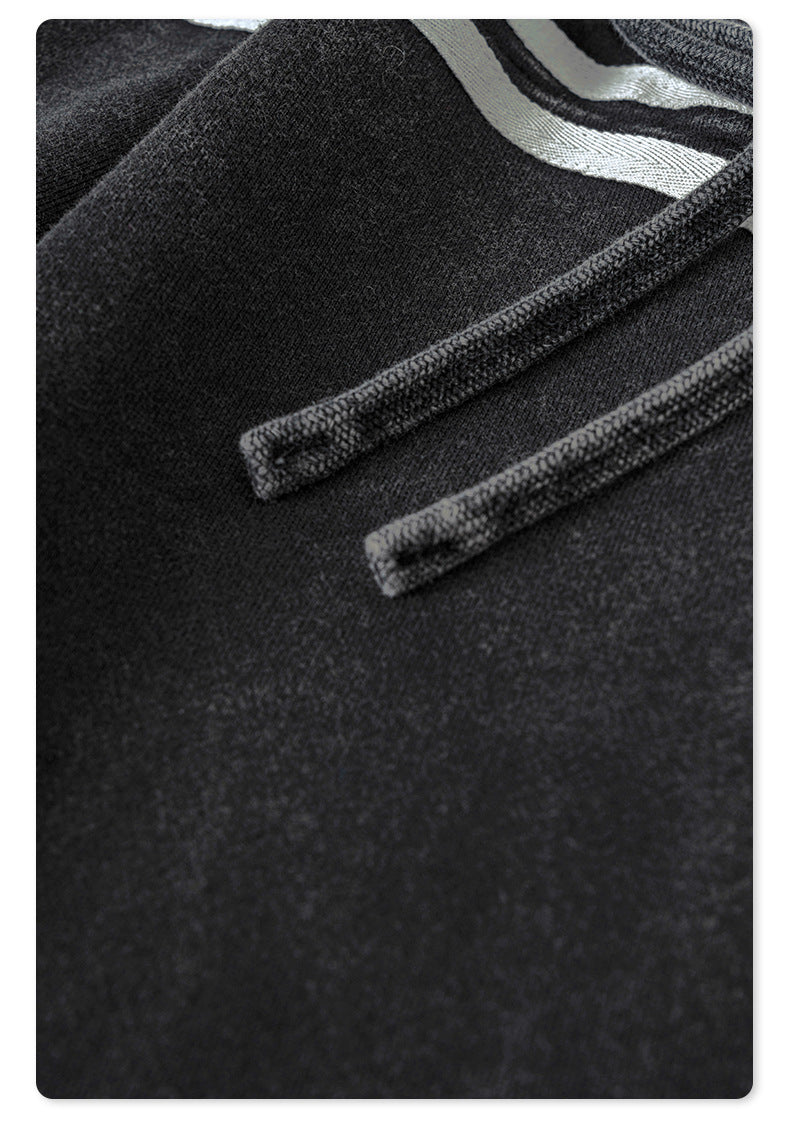 Close-up of gray drawstring detail on black track pants showing contrast stitching and textile texture
