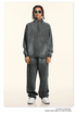 Model with twisted hair in slate gray half-zip pullover and matching pants, square sunglasses, silver jewelry, white sneakers