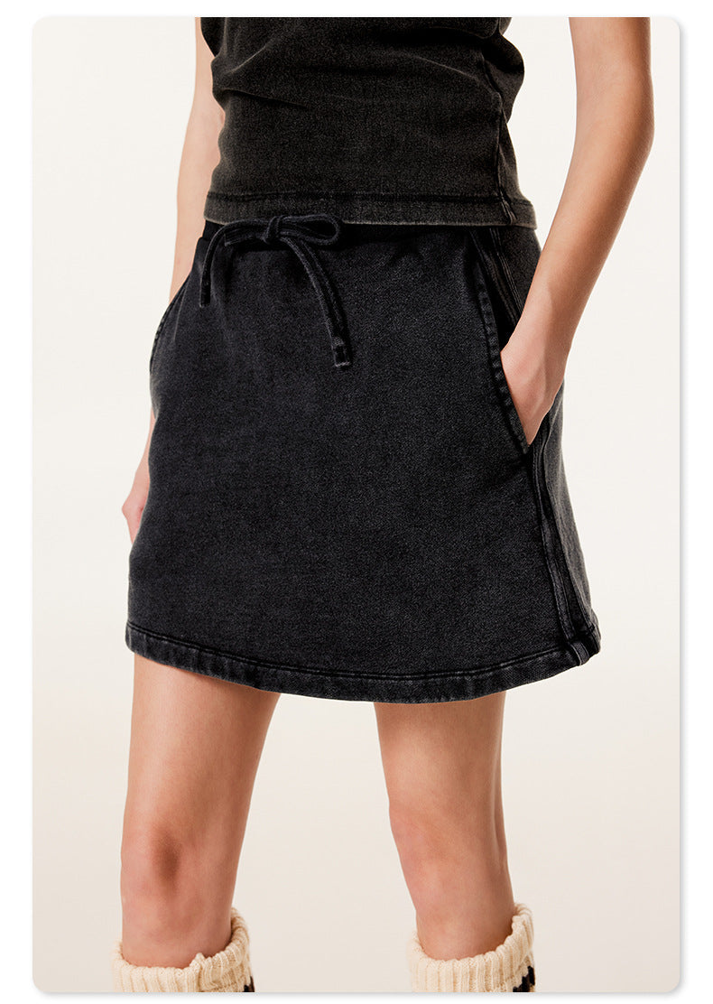 Close-up view of black mini skirt showing drawstring waist detail and comfortable fit against white background