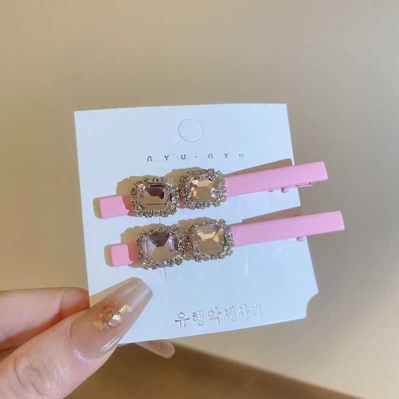 Pink alligator clips with double rectangular faceted crystals, surrounded by rhinestones, displayed on a card.